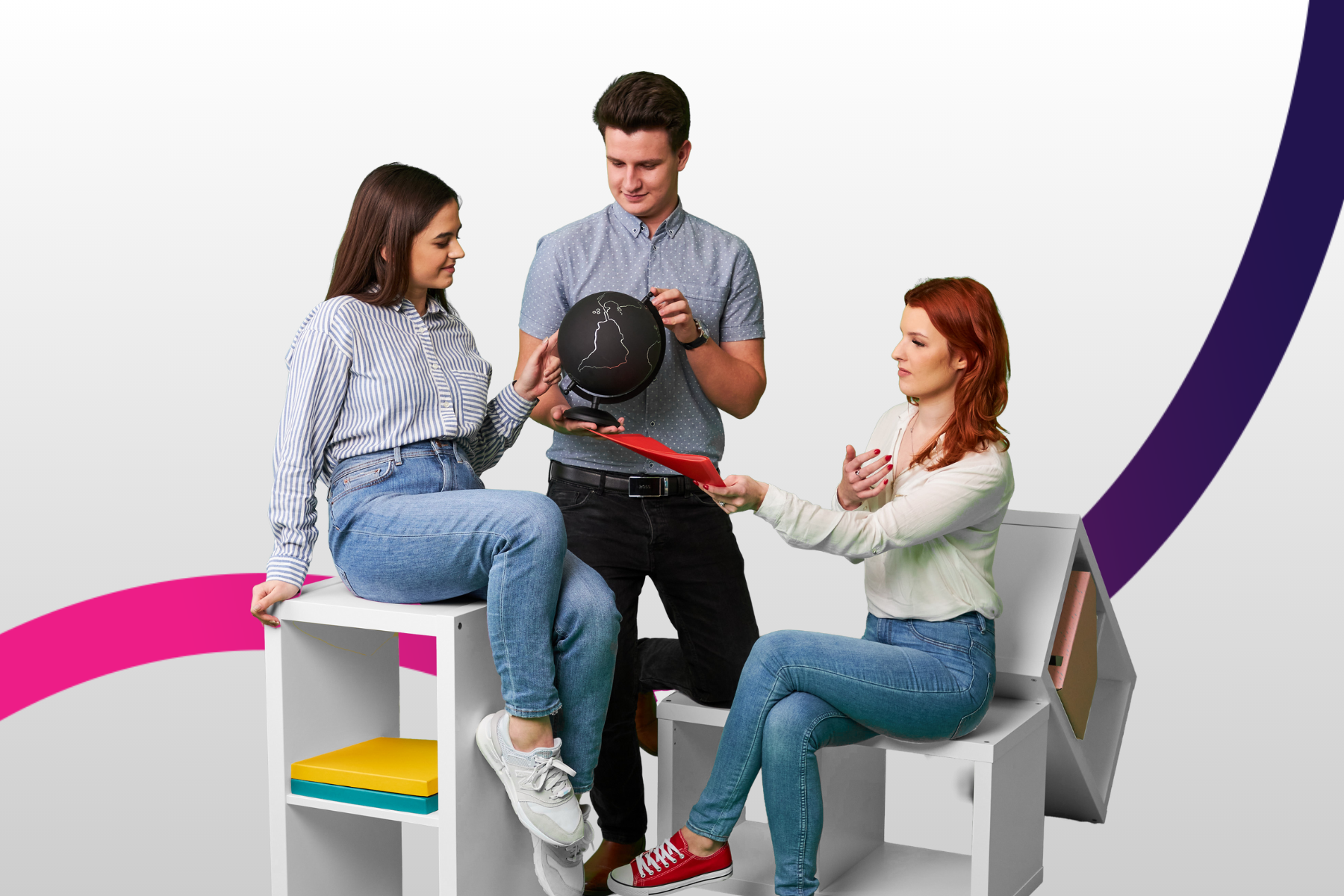 Trójka studentów dwie dziewczyny siedzą po środku stoi chłopak z czarnym globusem