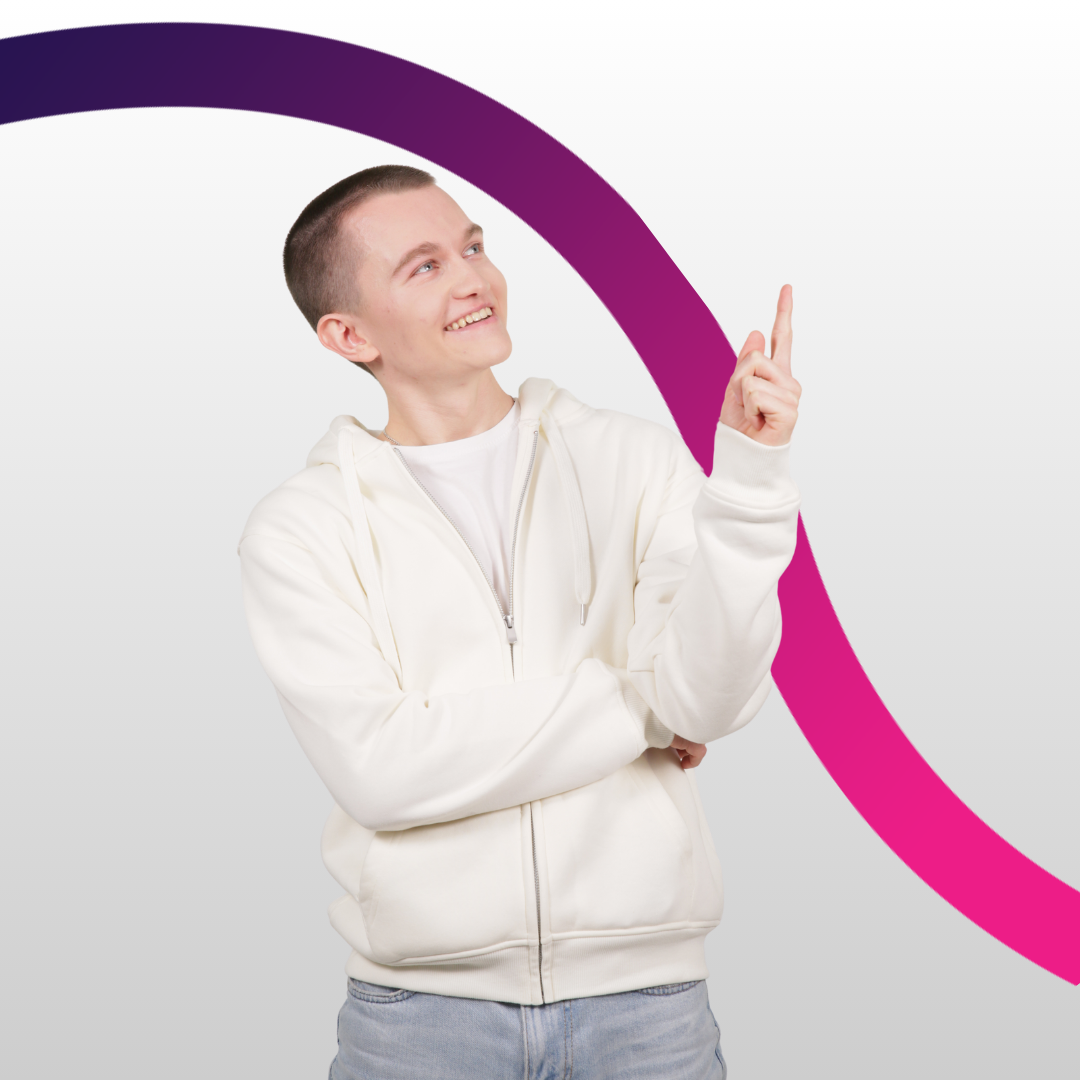 Chłopak w białej bluzie i jasnych jeansach stoi uśmiechnięty patrzy się w prawo i podnosi rękę z palcem do góry jakby wpadł na jakiś pomysł