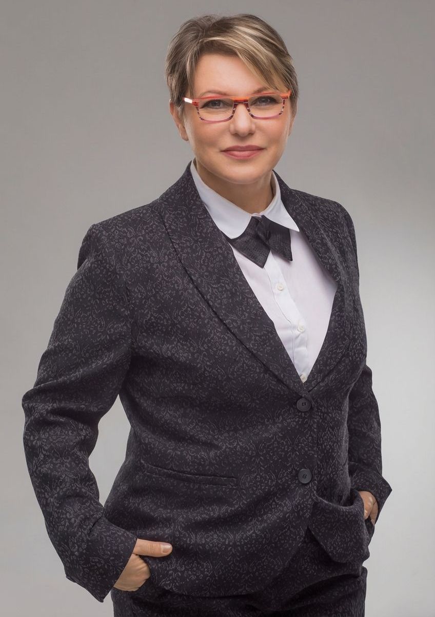Zdjęcie Marii Christowa - Dobrowolskiej. Kobieta w ciemnym garniturze, białej koszuli i okularach.